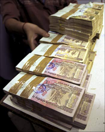 A bank employee counts bundles of Indian currency.