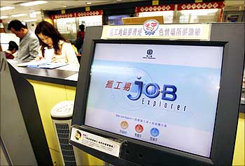 Job seekers go through vacancies beside a monitor at a Labour Department job centre in Hong Kong.