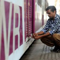 A rail employee looks the door of a Mumbai local train