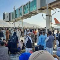 Afghans clamber on top of a plane at Kabul airport