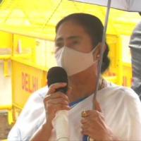 Mamata Banerjee holds her own umbrella while speaking to reporters
