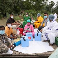 Healthcare workers cross a river to inoculate villagers