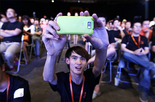 A user of Xiaomi uses his mobile phone to take a photo at a launch ceremony of Xiaomi Phone 2 in Beijing.