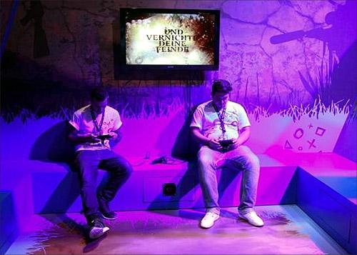 Visitors play Playstations at an exhibition stand during the Gamescom 2012 fair in Cologne.