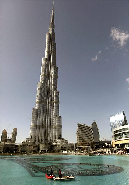 Workers move on a boat in an artificial lake at Dubai Mall in front of the Burj Khalifa.