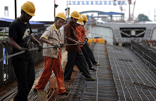 Labourers place steel reinforcement bars atop an unfinished steel box girder for a high-speed railway viaduct in Hefei, Anhui province.