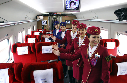 Attendants pose for pictures inside a high-speed train during an organized experience trip from Beijing to Zhengzhou, as part of a new rail line.