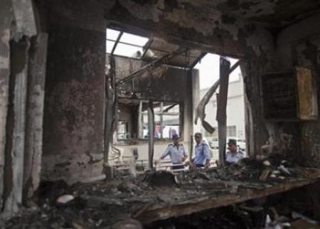 Private security guards stand behind a damaged reception block of Maruti Suzuki's plant in Manesar, located in Haryana.