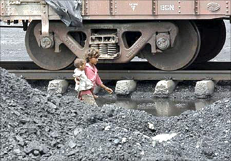Children of labourers walk beside a railway track inside a coal yard on the outskirts of Ahmedabad.