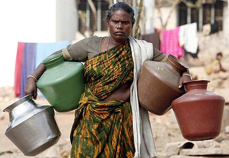 A woman walks to a tap to collect water on the outskirts of Bengaluru..