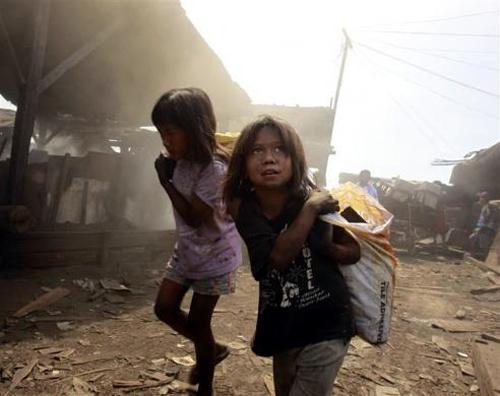 Girls carry sacks in a charcoal factory at a slum in Manila, Philippines.