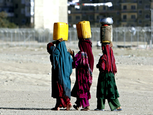 Afghan internal displaced refugee women carry water on their head near their shelter at the outskirts of Kabul.