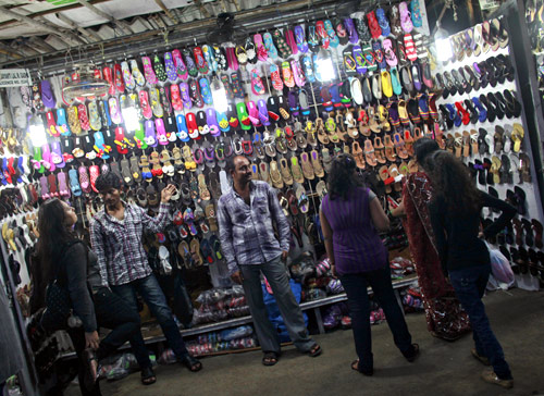 People shop for shoes at a roadside store at a market.