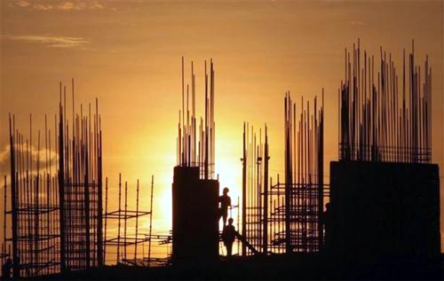 Image: Labourers are silhouetted against the setting sun as they work at the construction site of a residential building in Hyderabad.