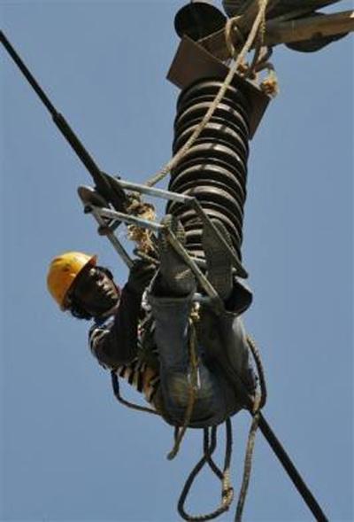 A labourer hangs on an electric power cable as he removes kites tangled up on it in Ahmedabad.