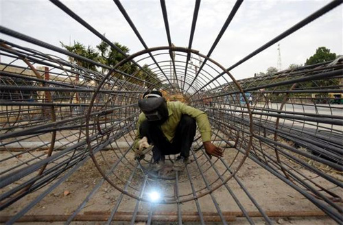 A worker welds iron rods at the Metro railway construction site in Kolkata.