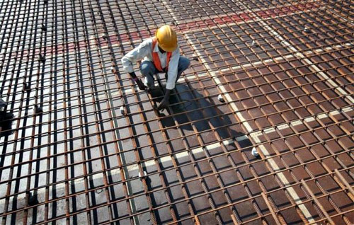A worker fastens iron rods together at the construction site of a bridge on Srinagar-Jammu national highway in the outskirts of Jammu.