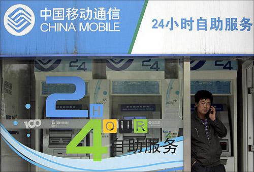 A man talks on his mobile phone at the entrance of a China Mobile booth in Beijing.