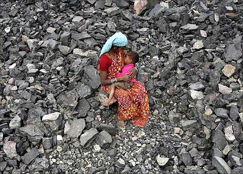 A worker breastfeeds her child during lunch break at a coal yard in Jammu.