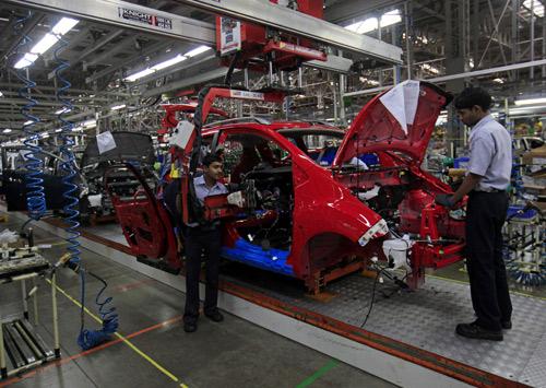 Employees work on a Chevrolet Beat car on an assembly line at the General Motors plant in Talegaon.