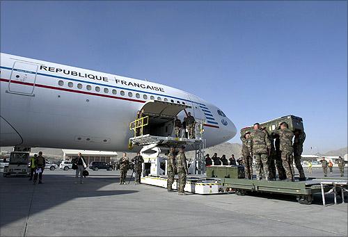 French troops load the flag-draped coffins of four soldiers onto a French plane during a ceremony at the airport in Kabul.