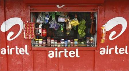 A vendor waits for customers at his grocery shop, painted with an advertisement for Bharti Airtel in Kochi.