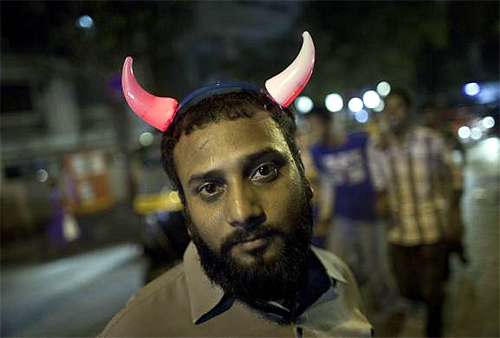Rehman, a streetside vendor, wears a pair of illuminated devil's horns as he waits for customers to buy his toys outside a fair in Mumbai.
