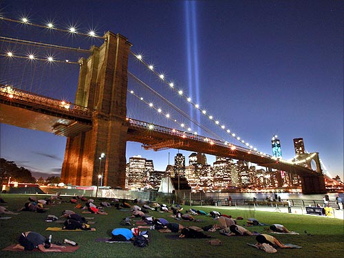 People take part in a sunset yoga session as the Tribute in Light shines over the Brooklyn Bridge.