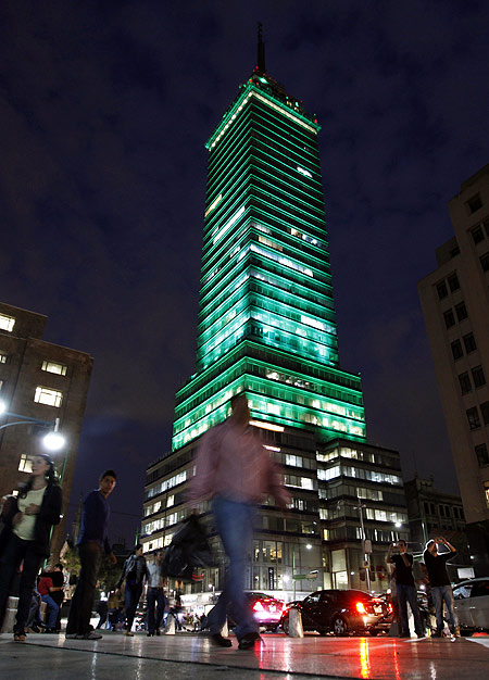 Pedestrians walk past the Torre Latinoamericana illuminated by LED lights, as part of an artistic intervention, in downtown Mexico City.