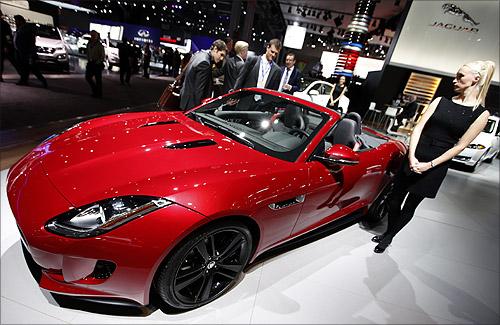 A model stands next to a Jaguar F Type S convertible model, winner of the 2013 World Car Awards World Car Design of the Year during a press preview at the 2013 New York International Auto Show in New York.