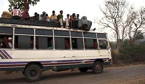 Tribal villagers sit atop of a bus as they travel through the remote district of Kandhamal in Orissa.