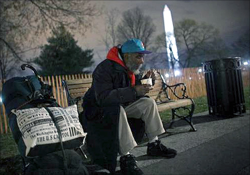 A homeless man sits on a bench with a cup of chili that he received from the Salvation Army in Washington.