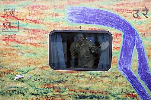 worker cleans a window pane of a passenger train at a railway station in Jammu.