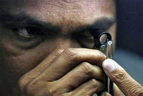 A supervisor checks the shape of a polished diamond inside the diamond processing unit at Surat, in Gujarat.