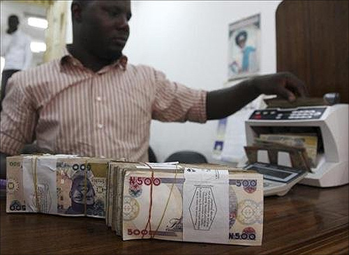 A money dealer counts the Nigerian naira on a machine in his office in the commercial capital of Lagos.