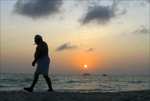 A man smokes a cigar as he walks along Seven Mile Beach in George Town, Cayman Islands.