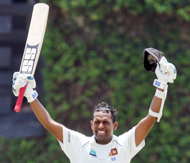 Sri Lanka's Thilan Samaraweera raises his bat and helmet to celebrate scoring his century against India