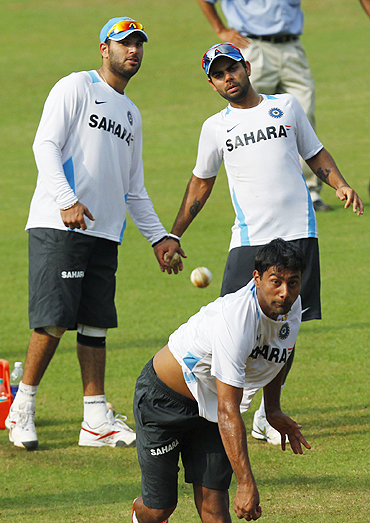 India's Praveen Kumar (centre) bowls as teammate Yuvraj Singh (left) and Virat Kohli look on during a practice session at Margao on Saturday