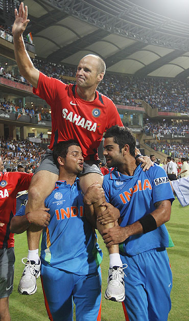 Gary Kirsten is lifted by Suresh Raina (left) and Virat Kohli (right)