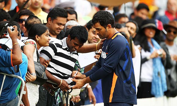 MS Dhoni signs autographs during a break in play on Monday