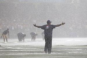 Groundsmen lay the covers on the field as the rain pours down at the Premadasa in Colombo