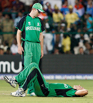 Trent Johnston of Ireland goes down after injuring his knee while bowling