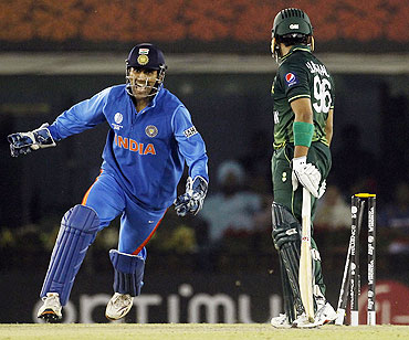 India's captain and wicketkeeper Mahendra Singh Dhoni (left) celebrates after Pakistan's Umar Akmal (right) is bowled by Harbhajan Singh