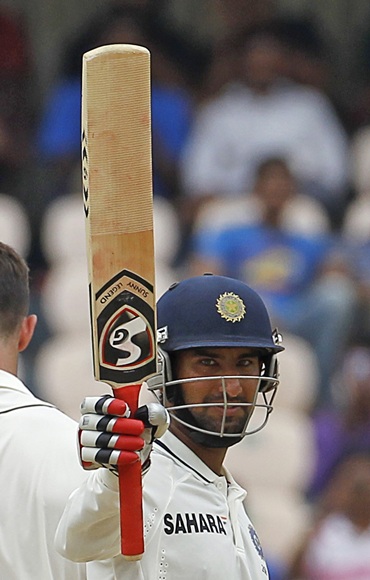 India's Cheteshwar Pujara raises his bat to celebrate scoring a half century during the first day of their first Test match