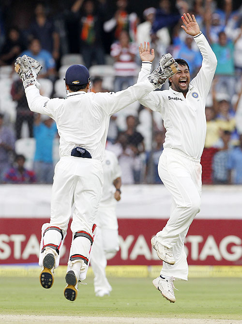 Pragyan Ojha (right) celebrates with captain Mahendra Singh Dhoni after claiming the wicket of Brendon McCullum