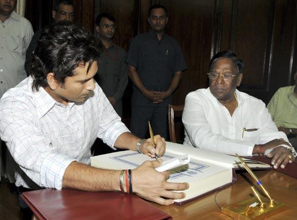 Sachin Tendulkar (left) signs the oath book as India's Minister of State for Parliamentary Affairs V Narayanasamy watches during the swearing-in ceremony