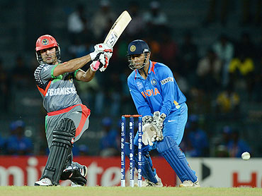 Afghanistan's Mohammad Nabi plays a shot on the on side as MS Dhoni watches