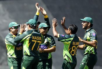 The Pakistan team celebrates the fall of a wicket