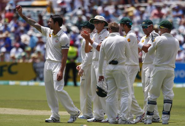Australia's Mitchell Johnson (L) shows the ball to the crowd as he celebrates taking five wickets in the inning