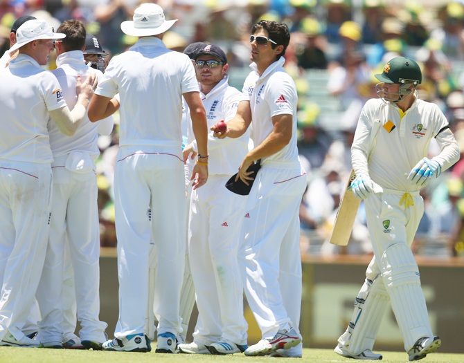 Michael Clarke of Australia looks back as the England team celebrate his wicket